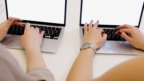two people typing on their laptops