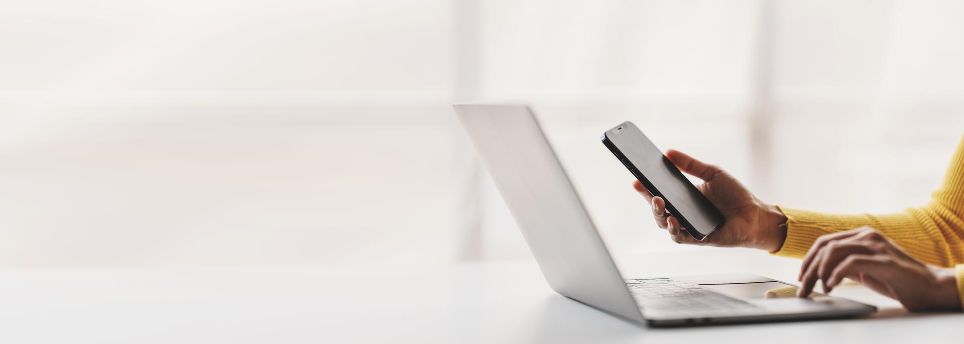 a person using a laptop and a smart phone
